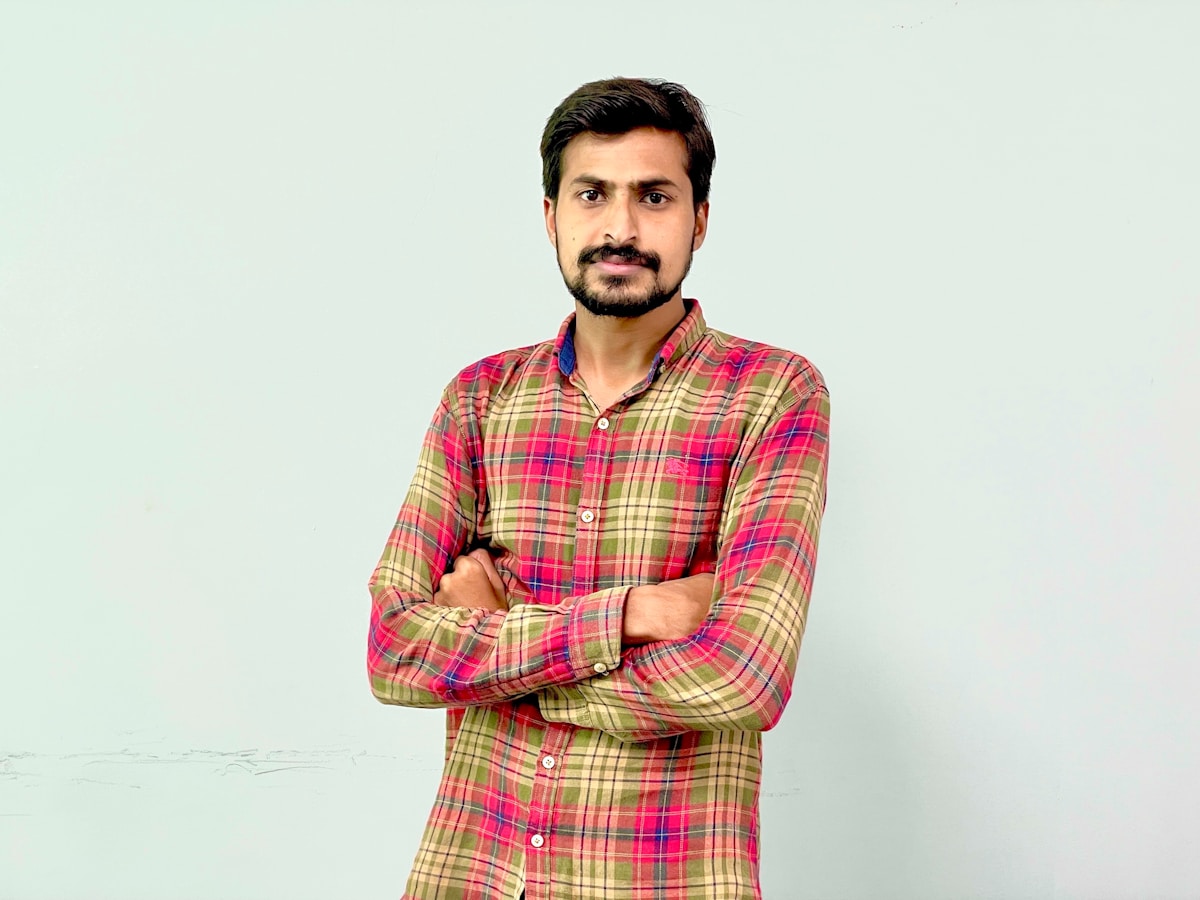 A man standing with his arms crossed in front of a wall
