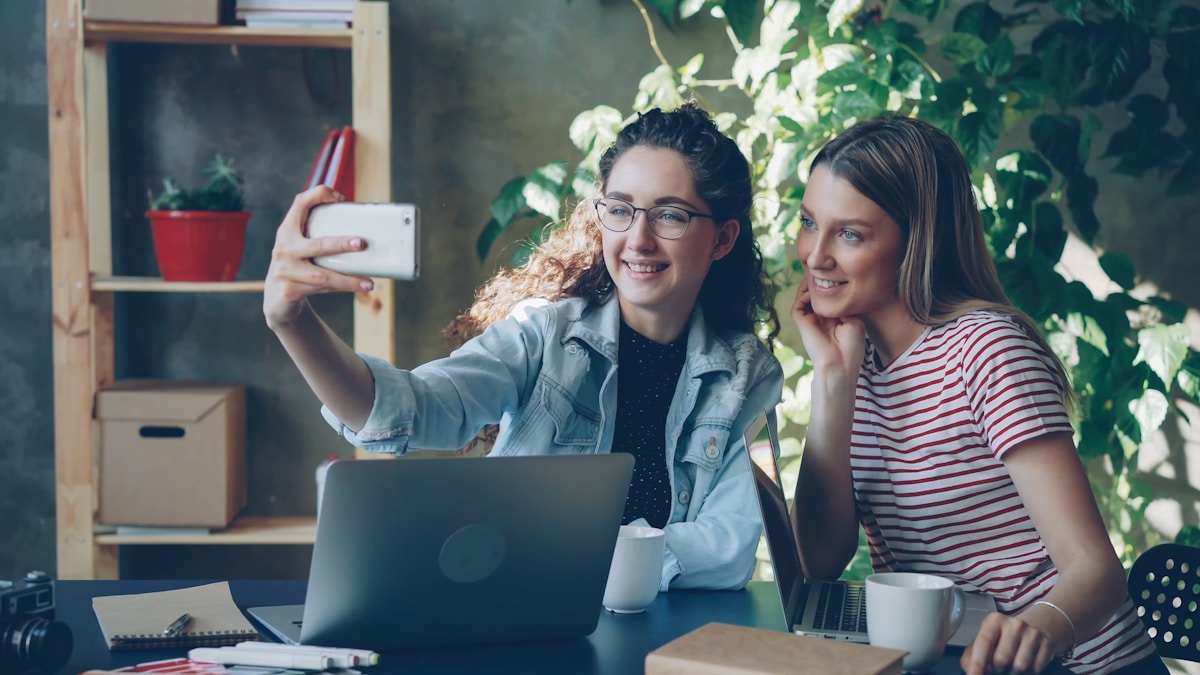 Two women smile while taking a selfie.