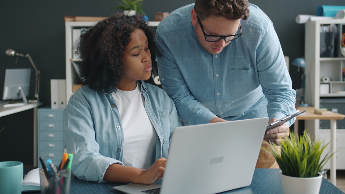 Deux personnes collaborant sur un ordinateur portable dans un bureau.