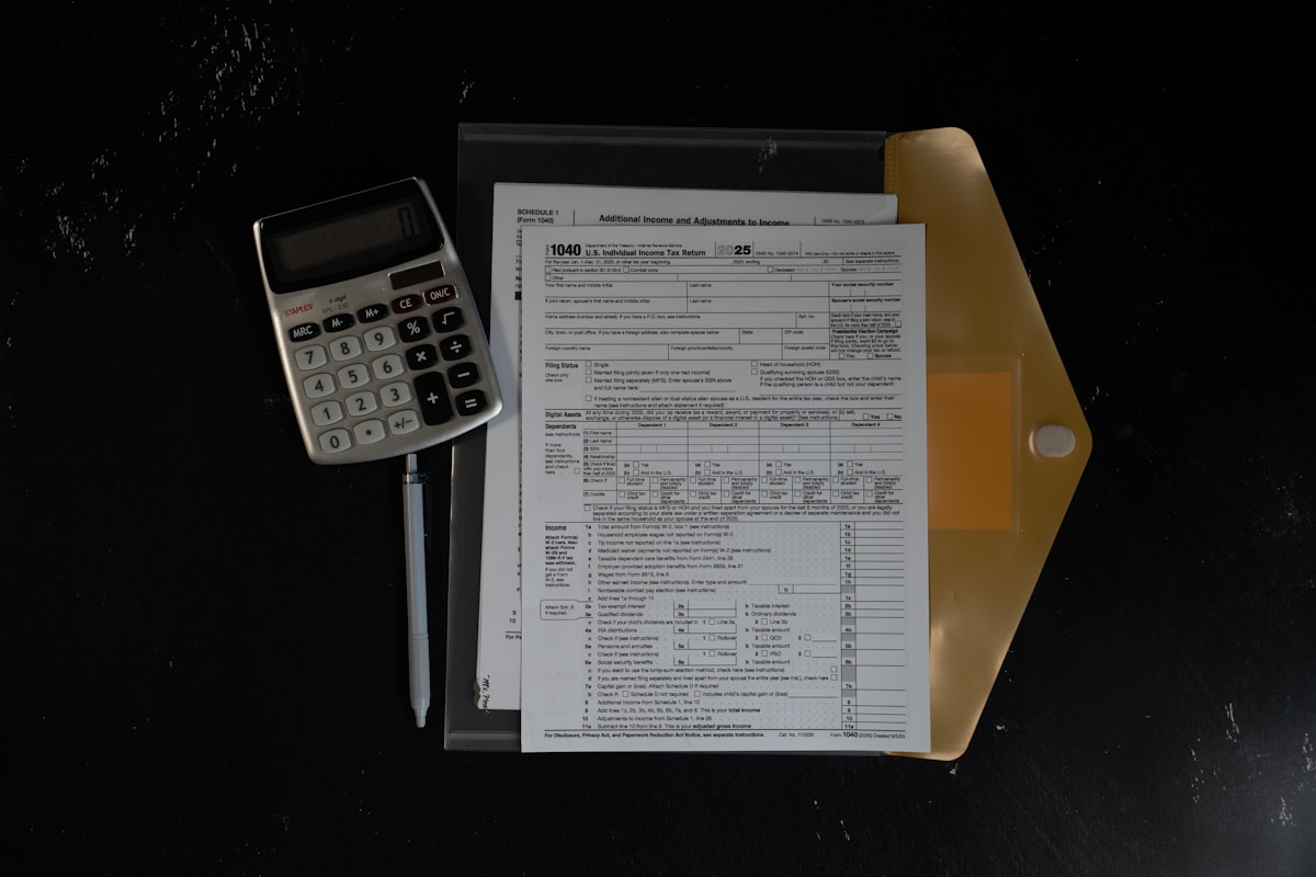 Formulaire fiscal, calculatrice et enveloppe sur fond noir.