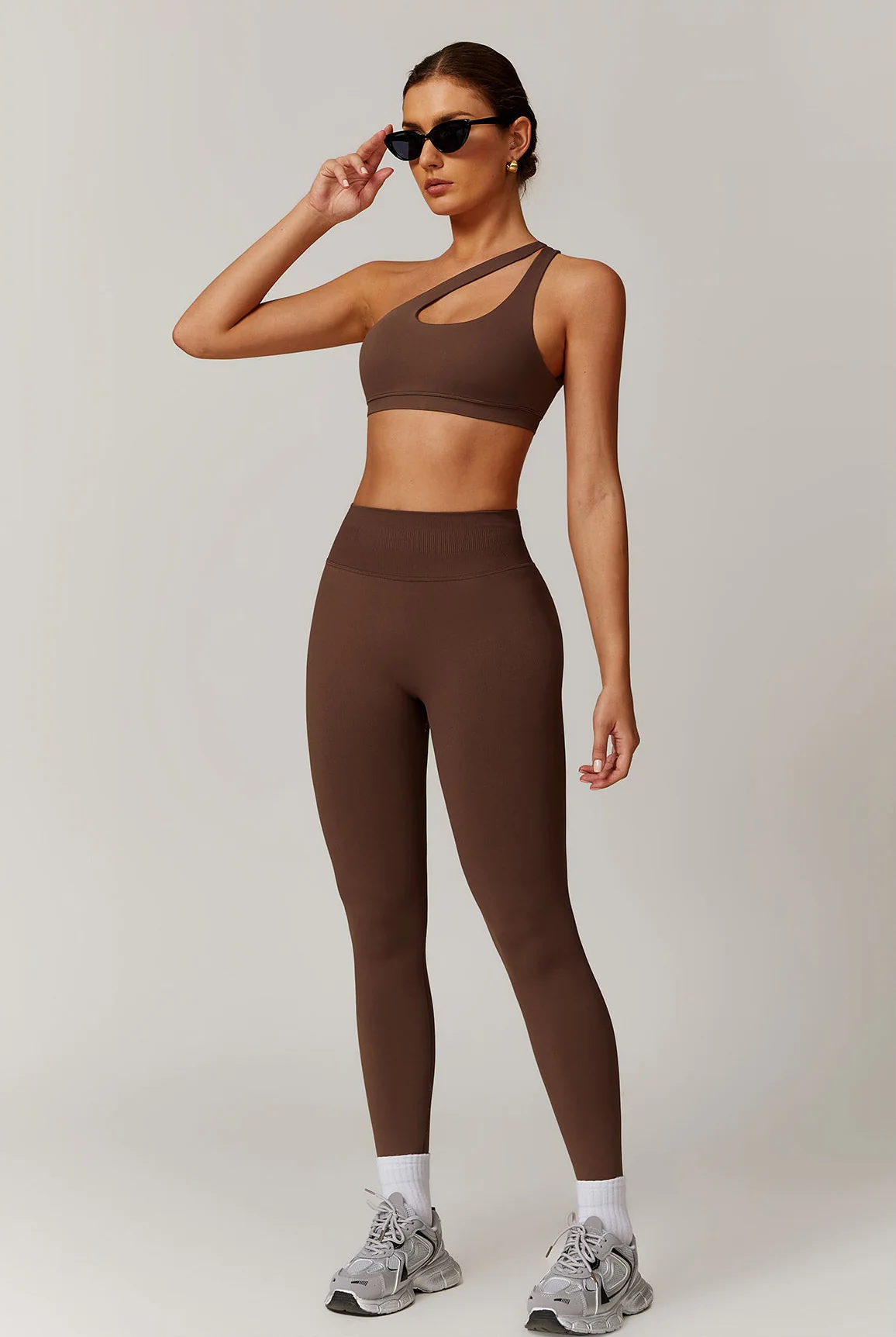 A confident woman walking in a city park wearing stylish high-waisted seamless leggings and a matching crop top, sunlight hitting the fabric to show texture. A confident woman walking in a city park wearing stylish high-waisted seamless leggings and a matching crop top, sunlight hitting the fabric to show texture.