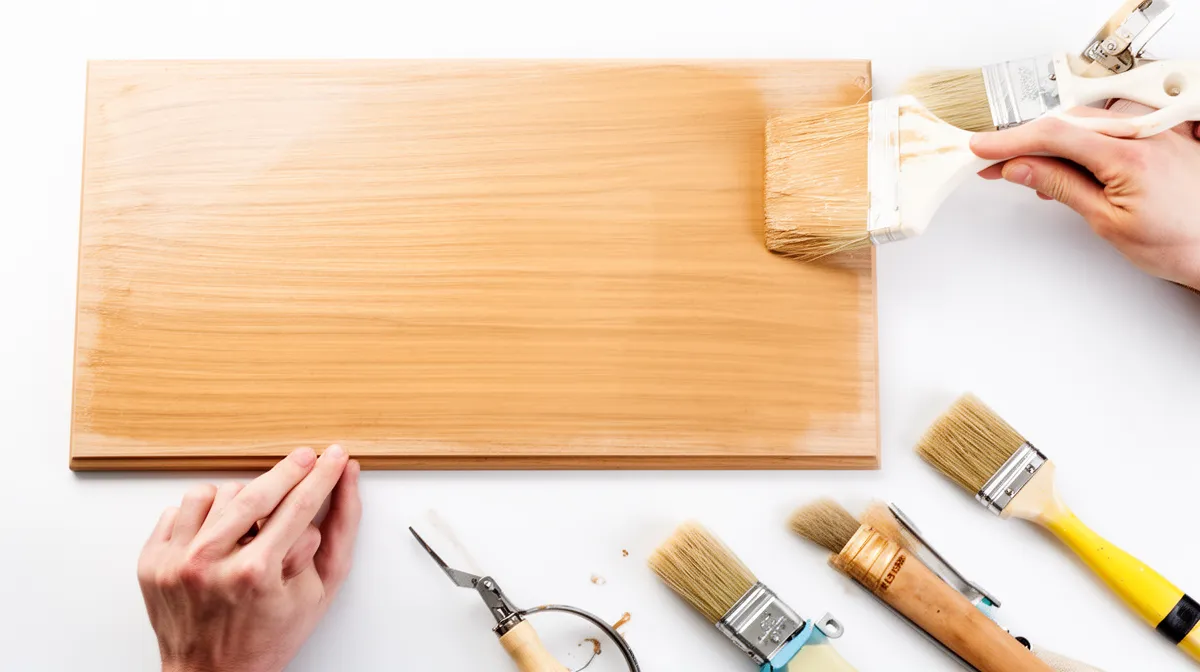 Pinceaux, outils de peinture et planche de bois sur fond blanc.