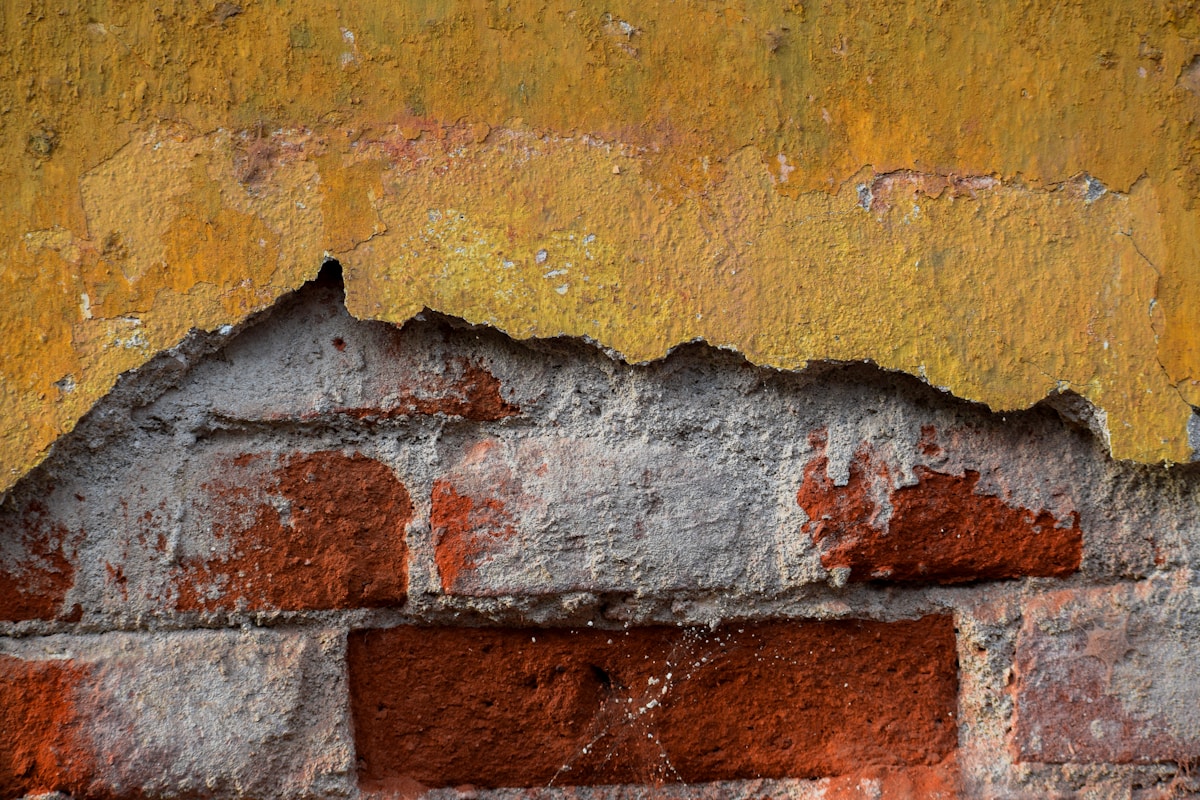 Mur de briques ancien avec couches de peinture écaillée et textures.