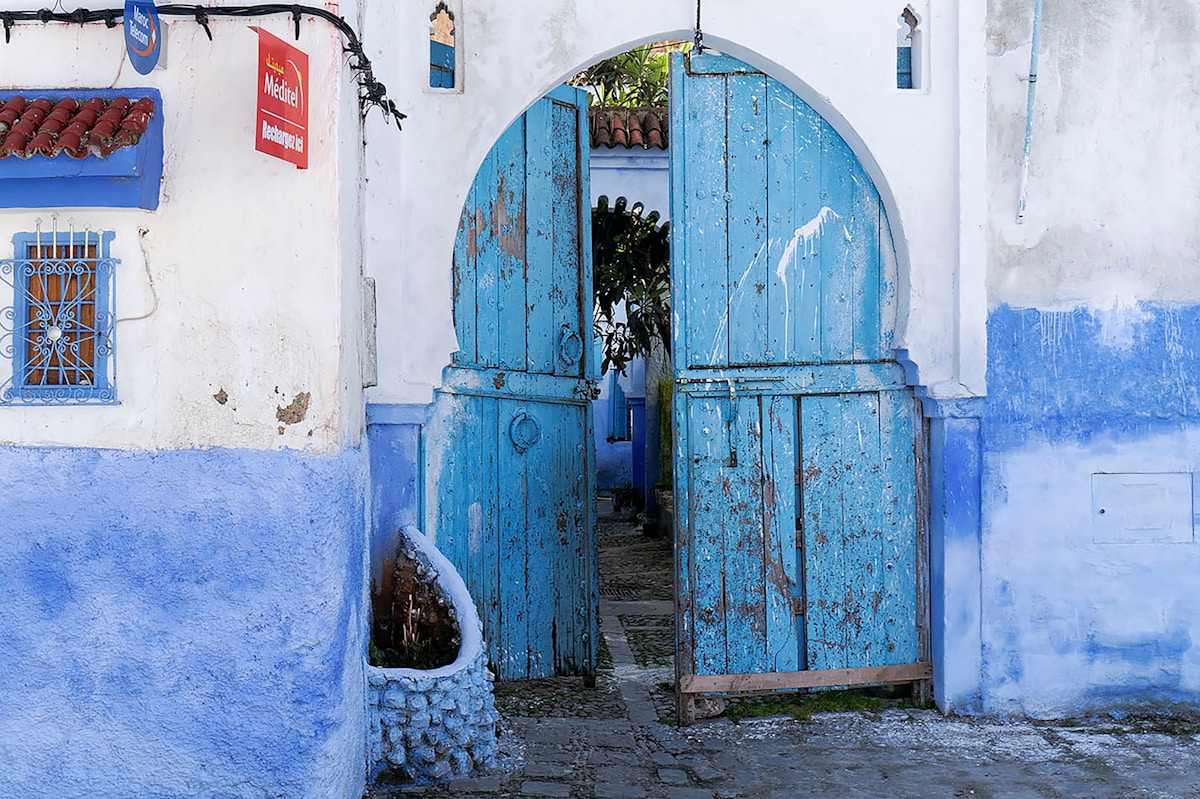 Ornate blue wooden doorway in a blue and white building.