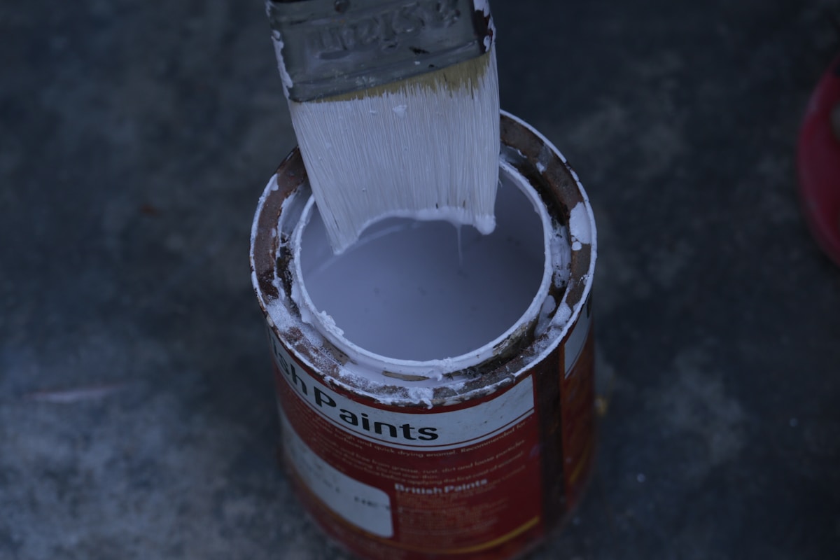 Pinceau de peinture plongé dans un pot de peinture rouge.