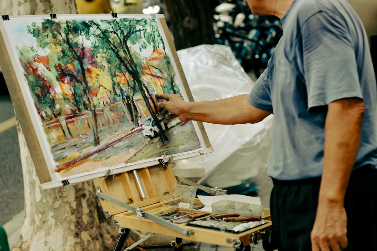 Artist painting a colorful outdoor scene on easel