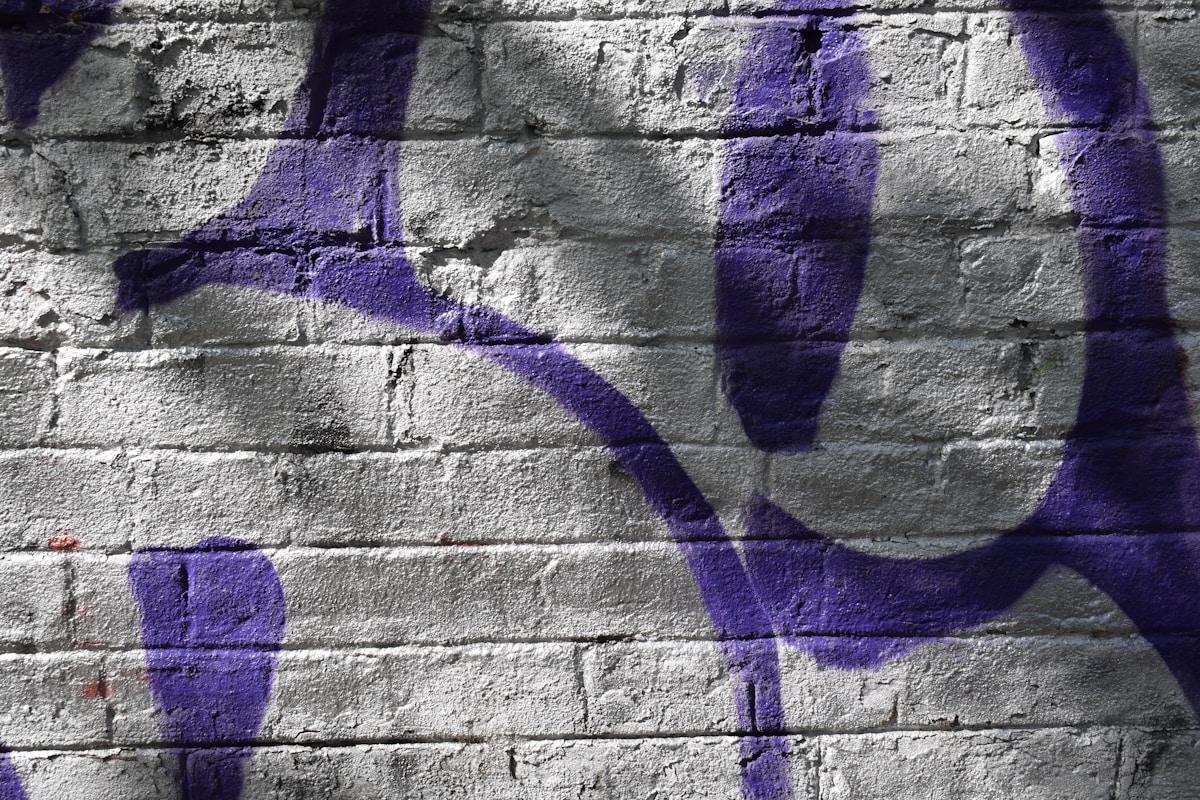 Mur de briques gris avec des formes géométriques violettes.