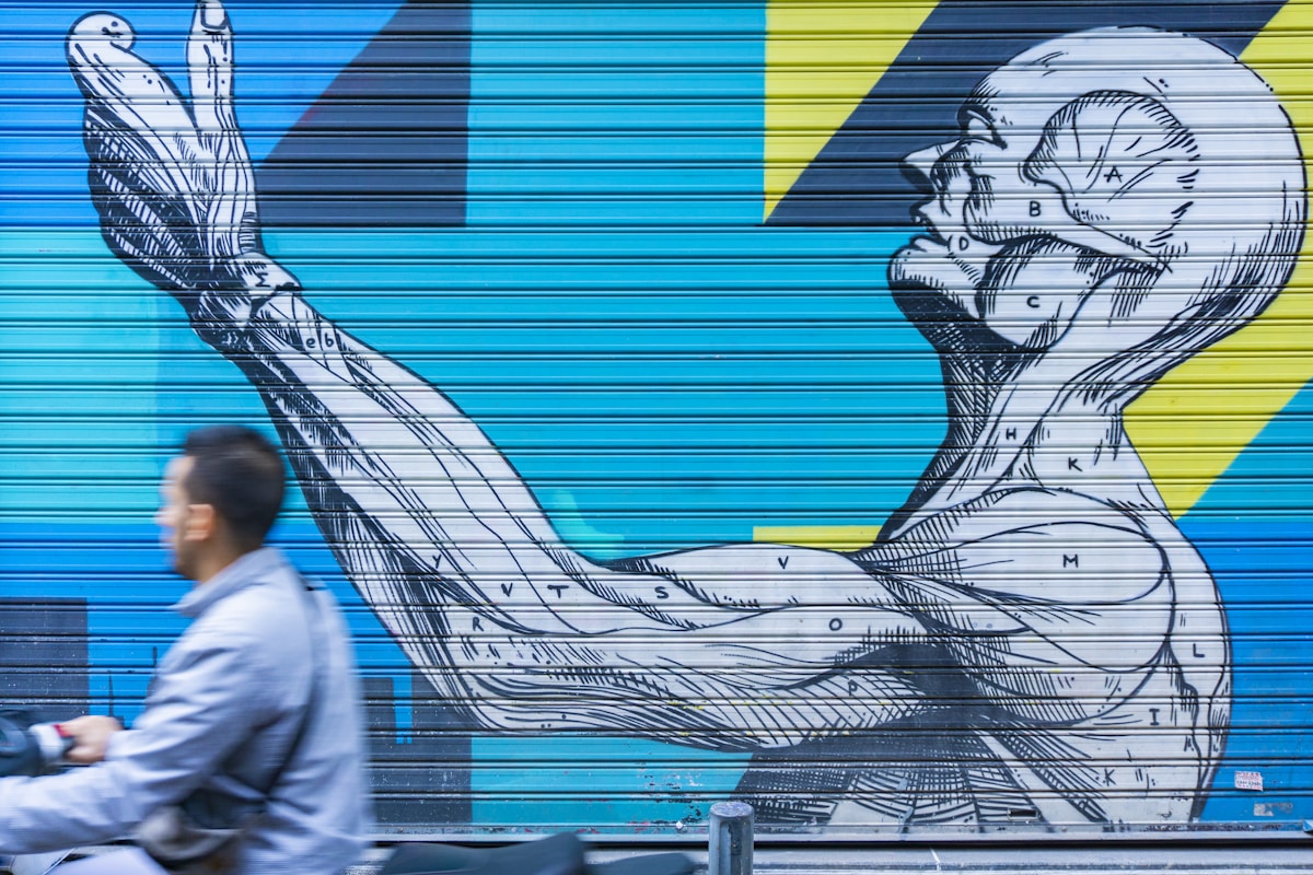 Graffiti mural représentant une figure humaine abstraite sur un fond bleu et jaune.