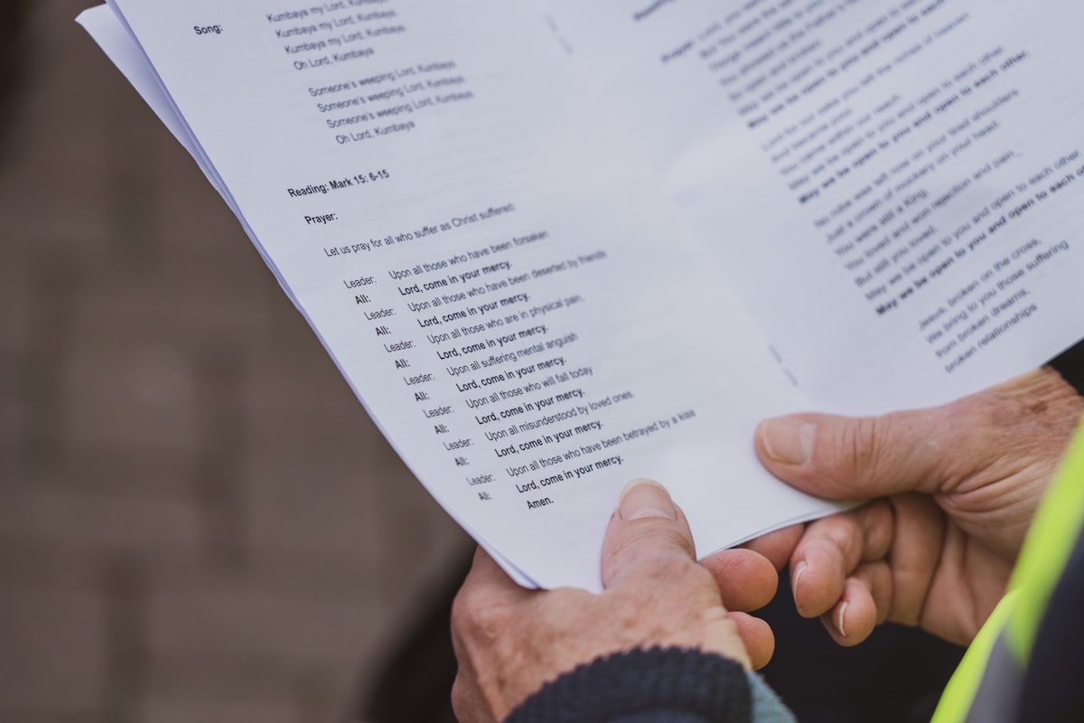Feuille de prière avec texte religieux dans les mains d'une personne.