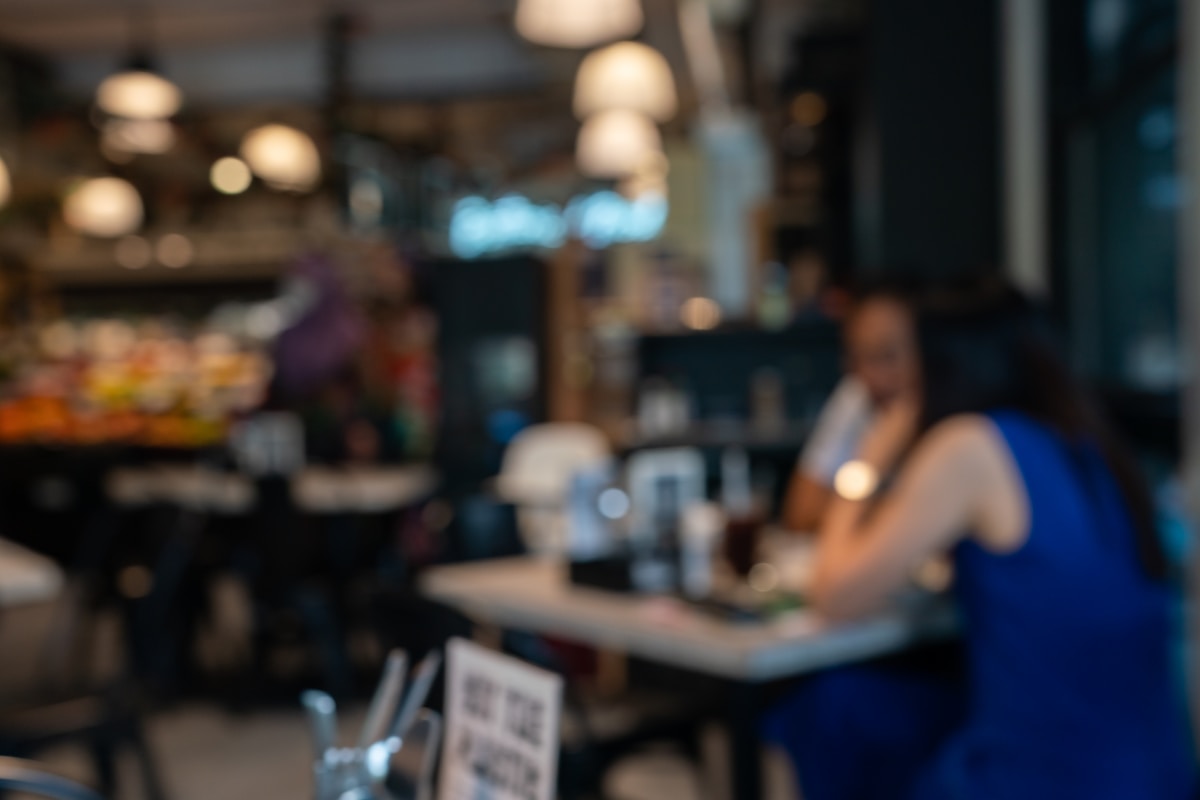 Intérieur flou d'un café avec des lumières tamisées et des gens assis.