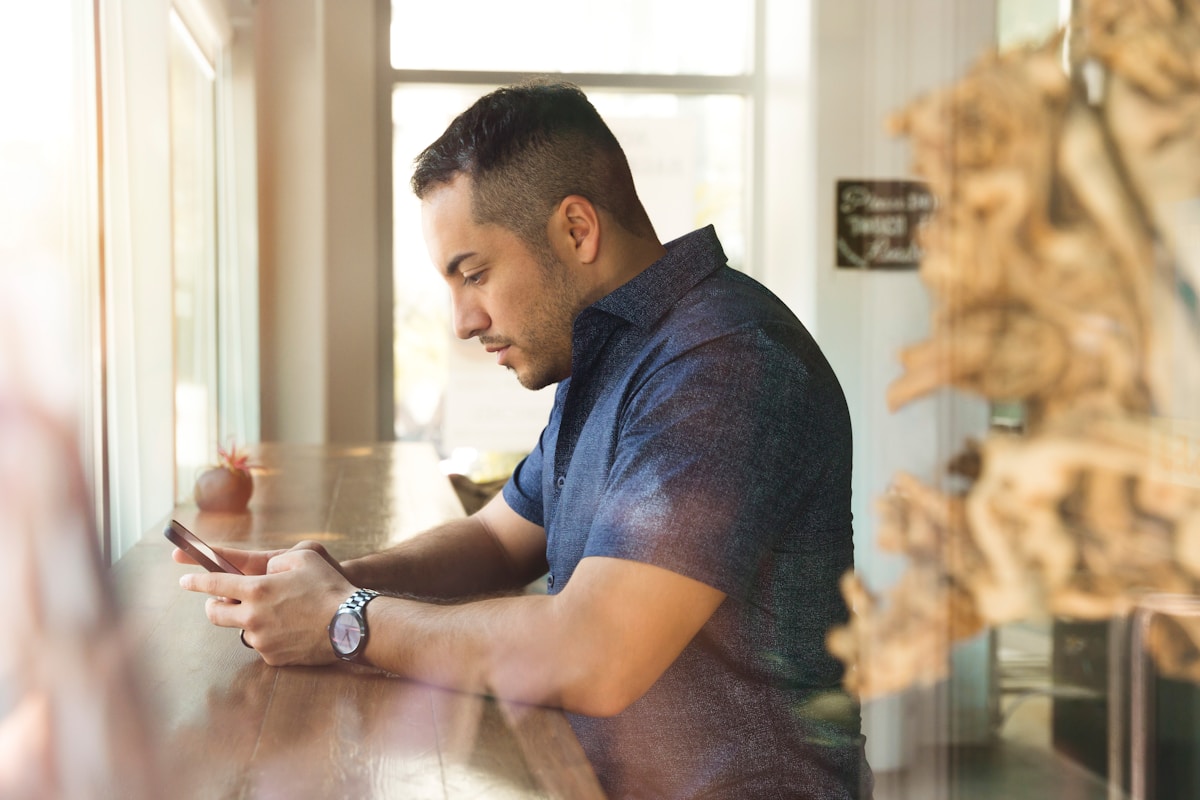 Un homme en chemise noire tenant un smartphone.