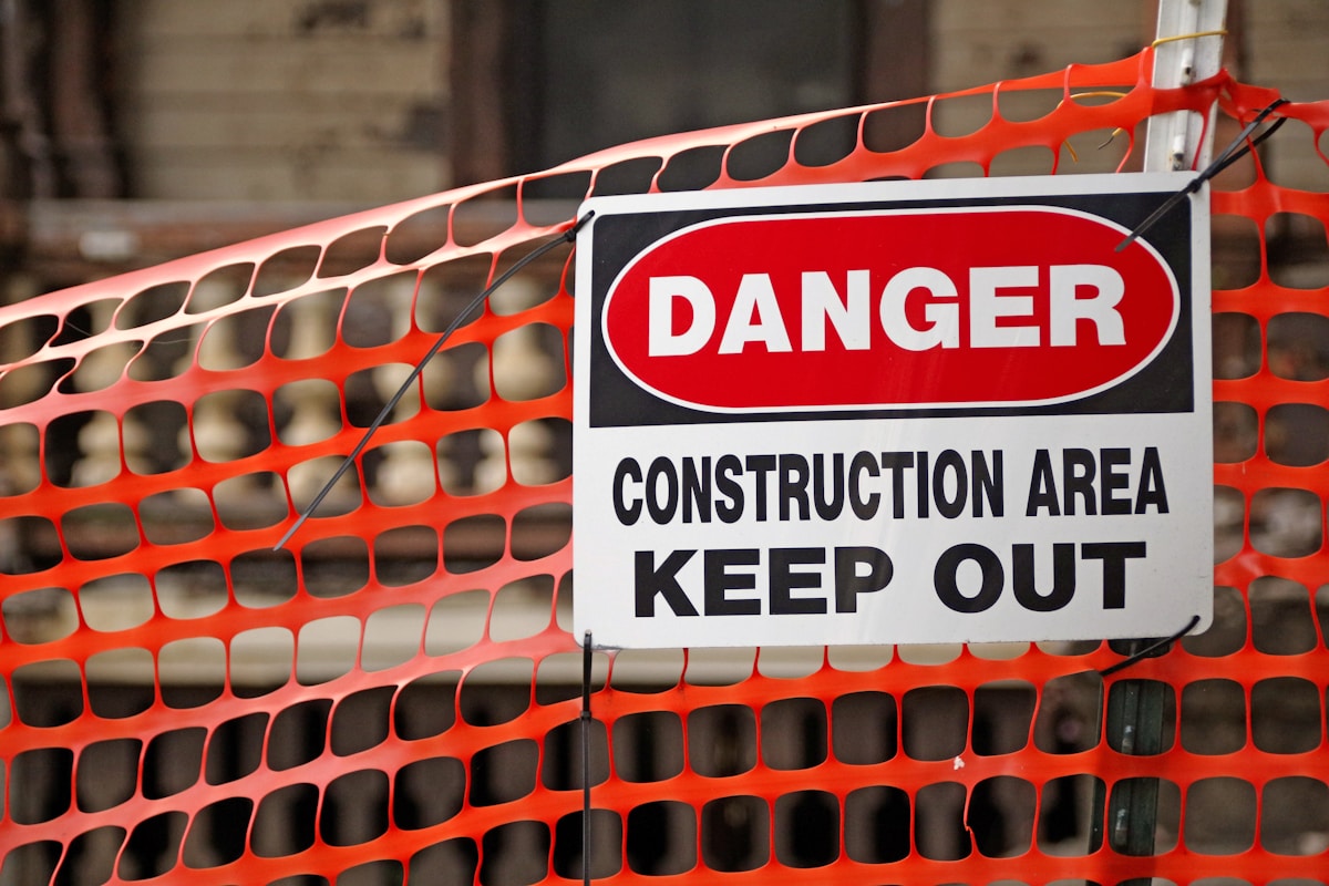 Panneau de danger indiquant une zone de construction avec barrière orange.