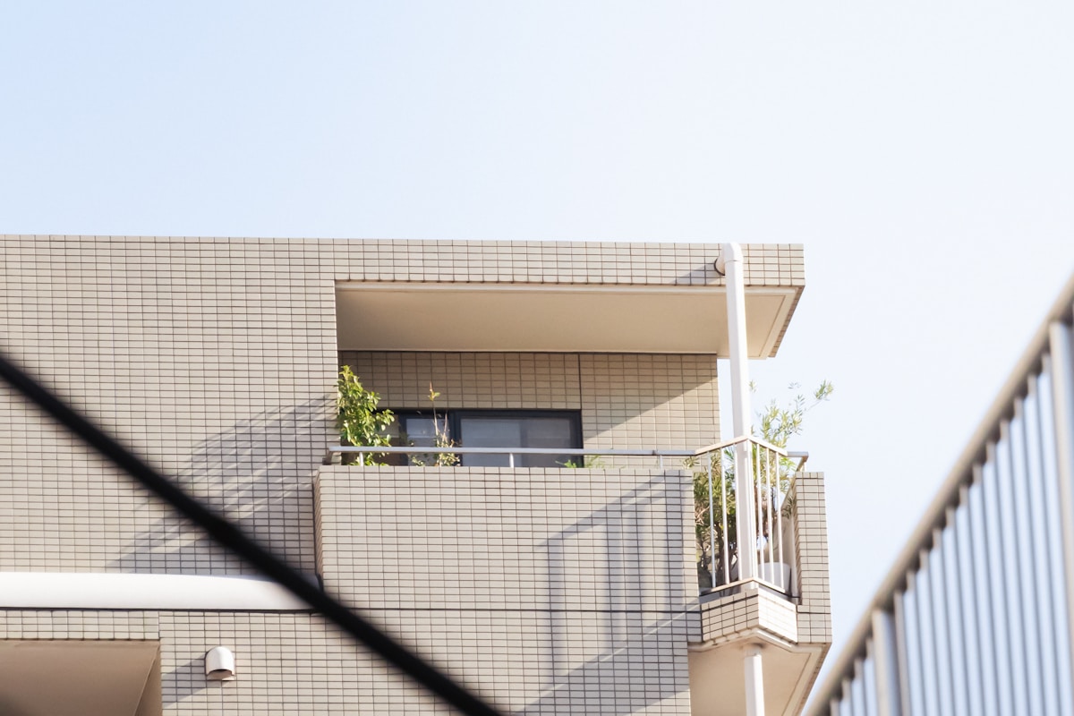 Bâtiment moderne en briques beige avec balcons et fenêtres.