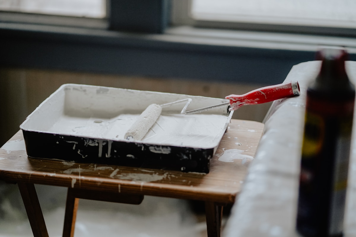 Boîte de peinture noire avec rouleau sur table en bois.