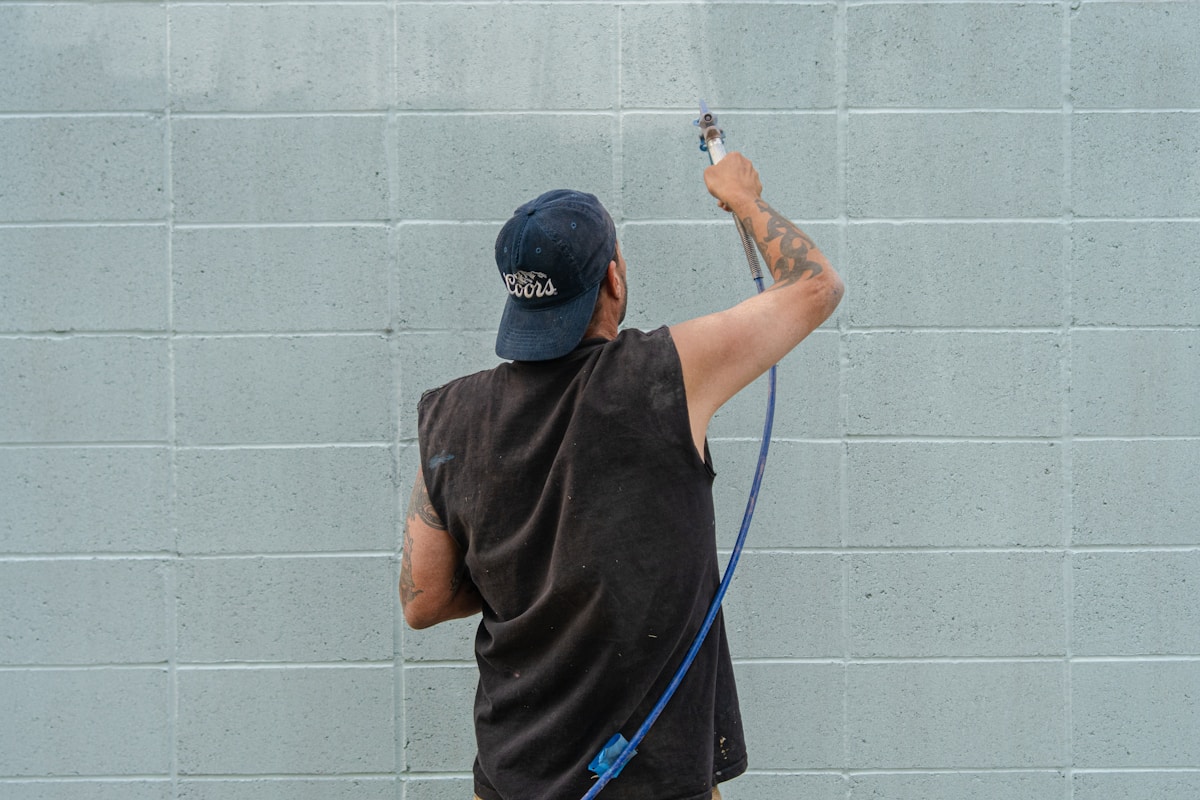 A man is painting a wall with a sprayer.