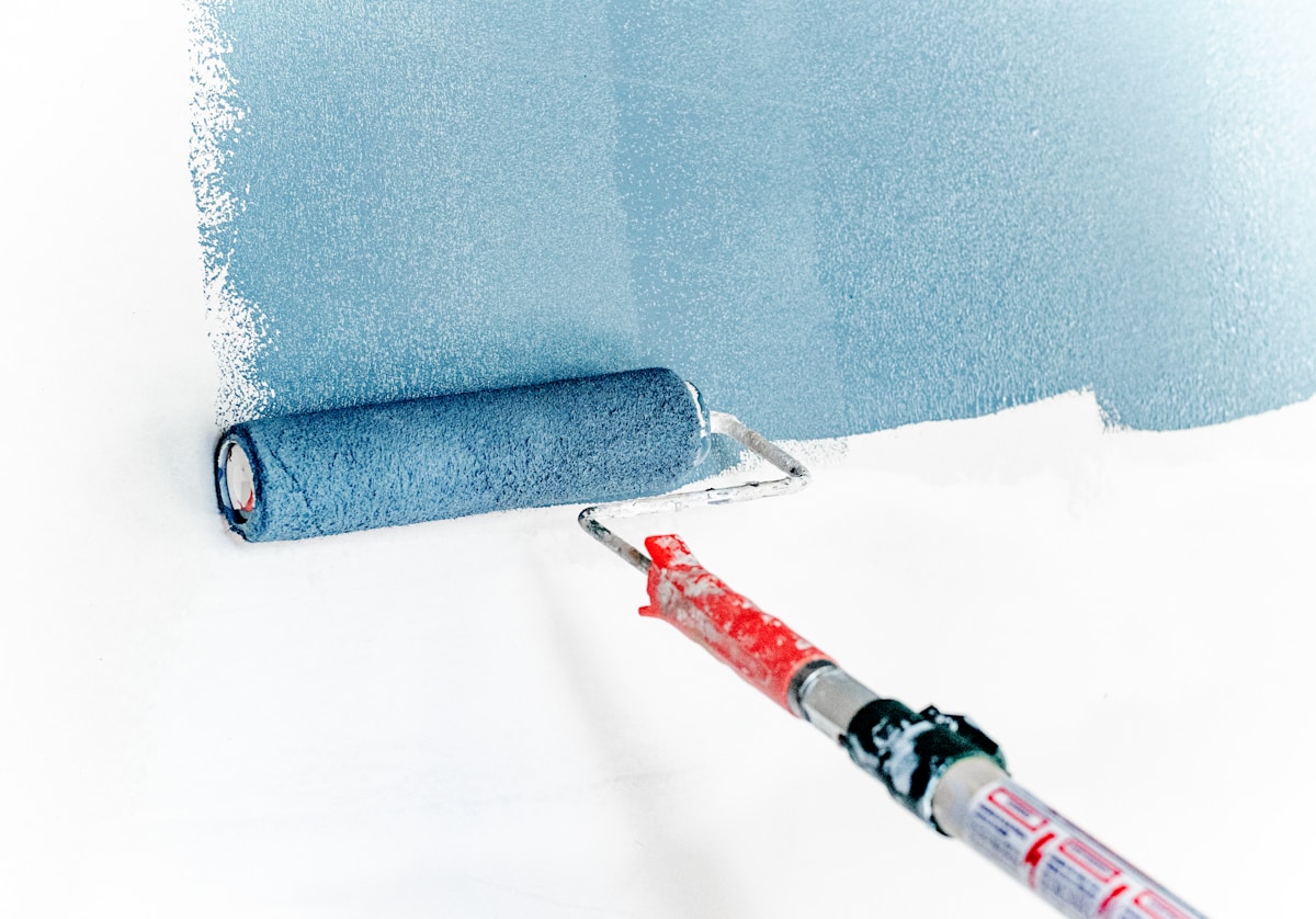 Peinture murale bleue avec rouleau de peinture rouge.