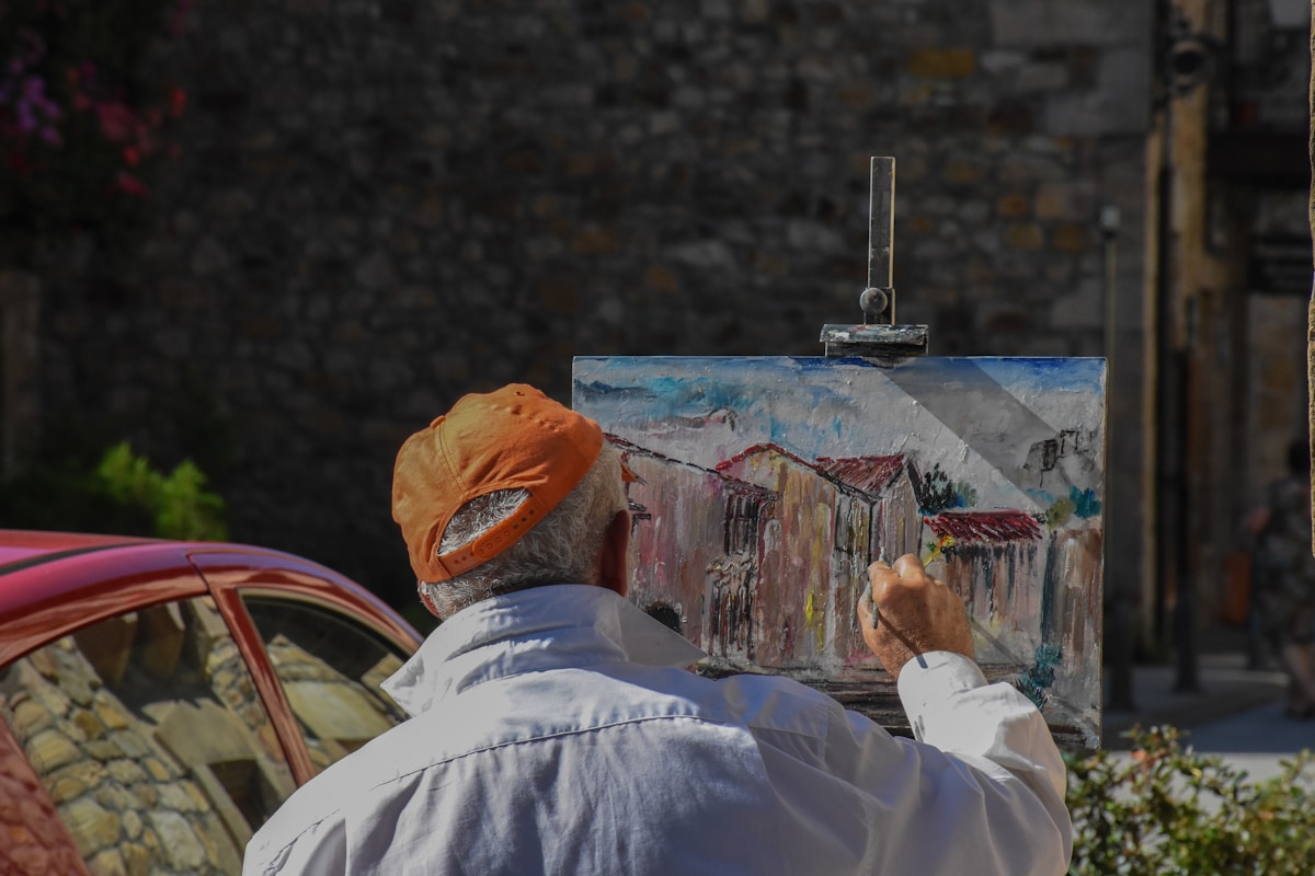 Artiste peignant une scène de village sur une toile en plein air.