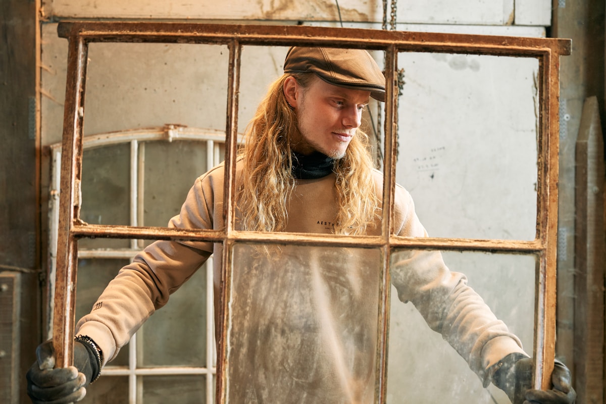 A woman wearing a hat and gloves standing in front of a window