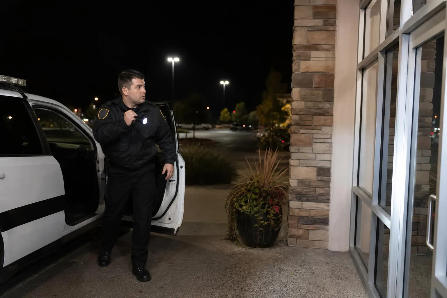 Police officer standing near a building at night.