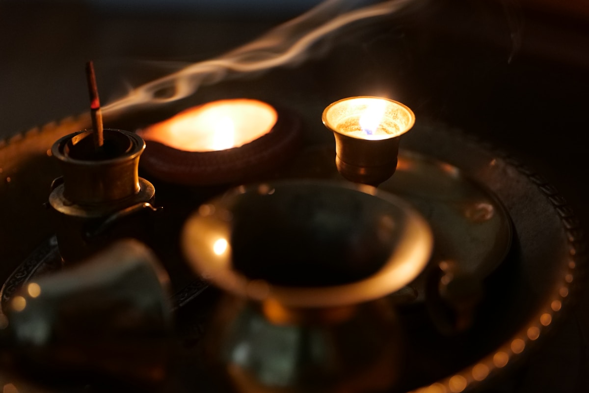 Bougies allumées, vapeur, tasses, plateau en métal, ambiance feutrée.