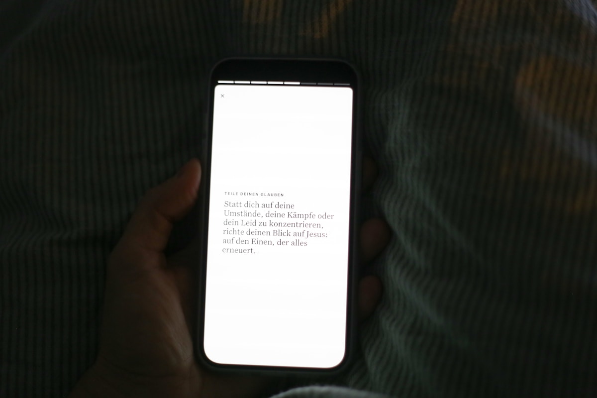 Hand holding smartphone with bright white screen.
