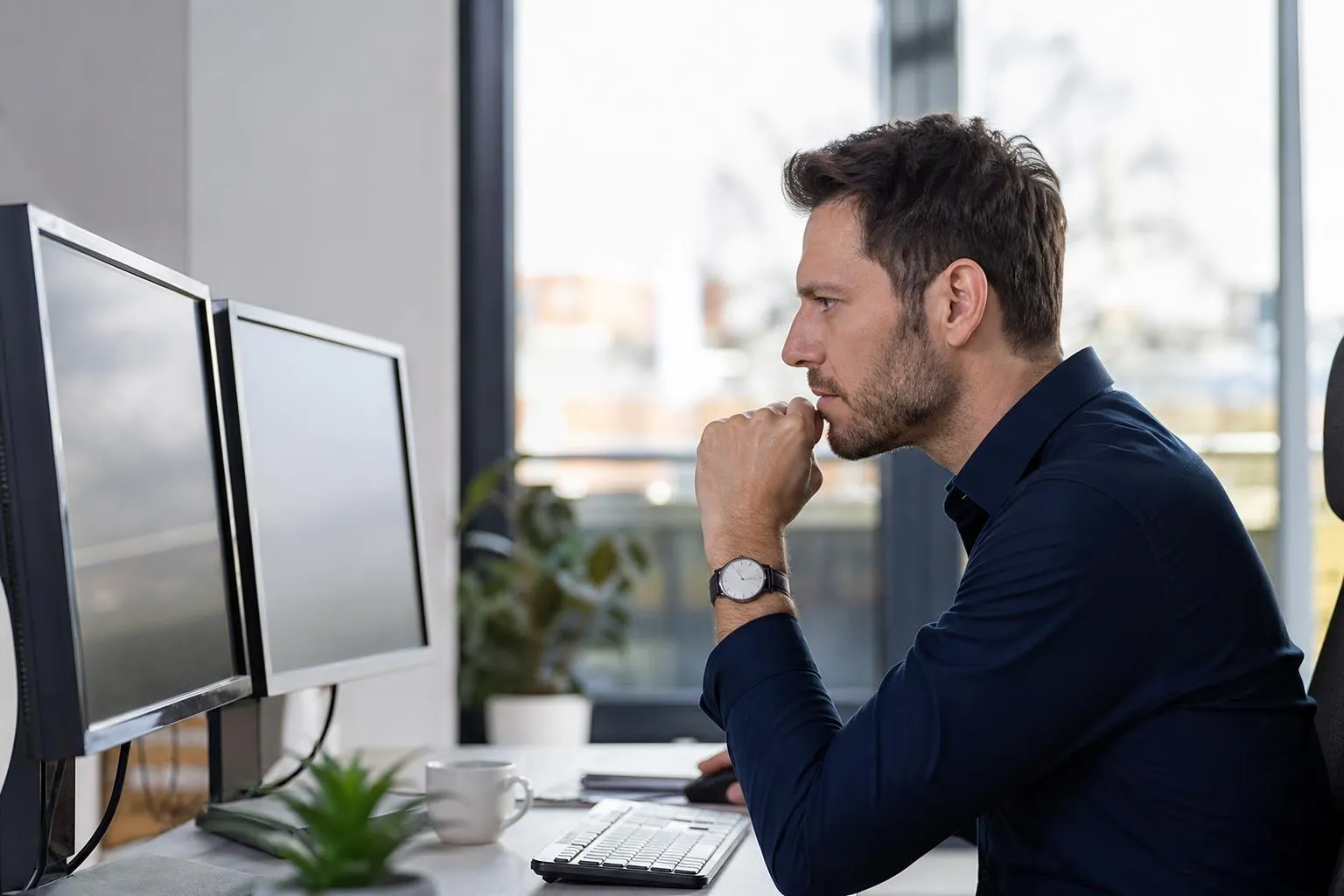 Businessman working intently on computer in office environment.