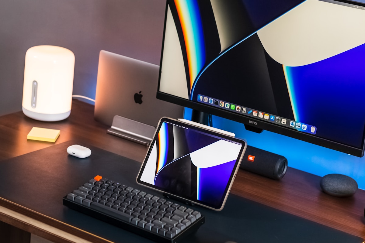 a desk with a keyboard, monitor, mouse and cell phone