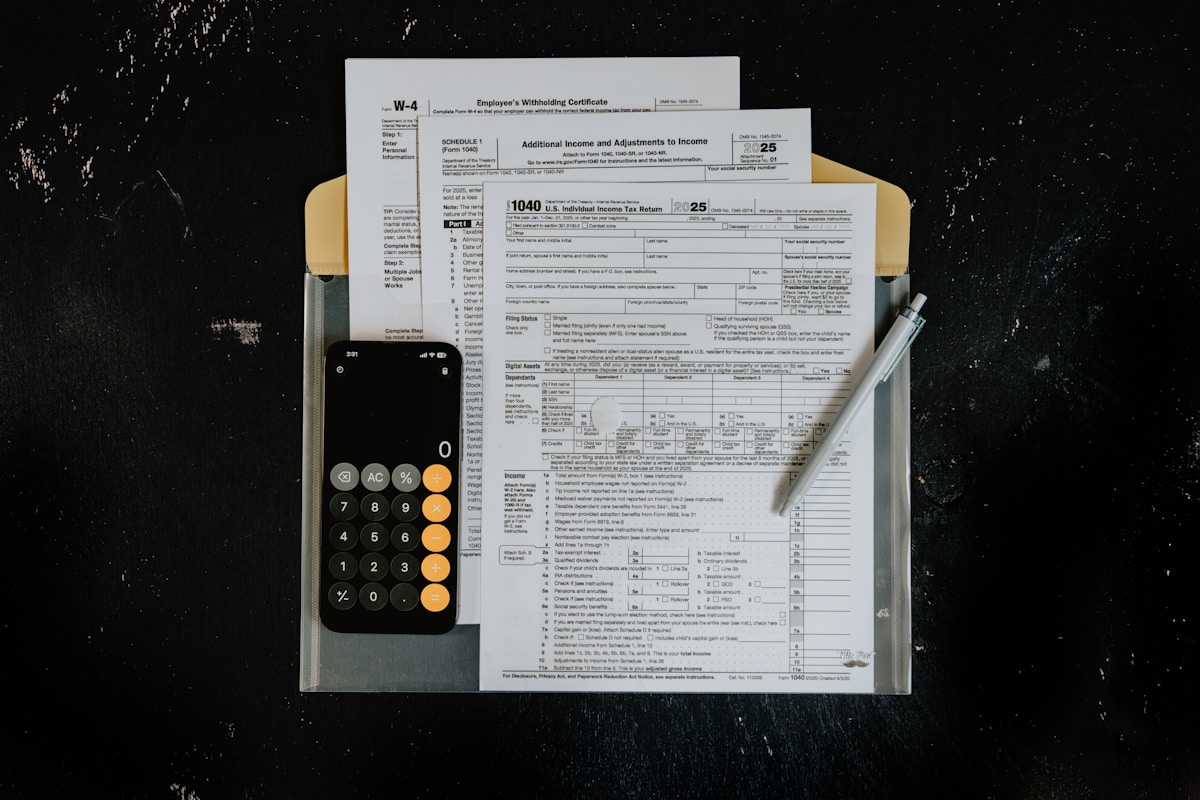 Tax forms with calculator and pen on dark surface