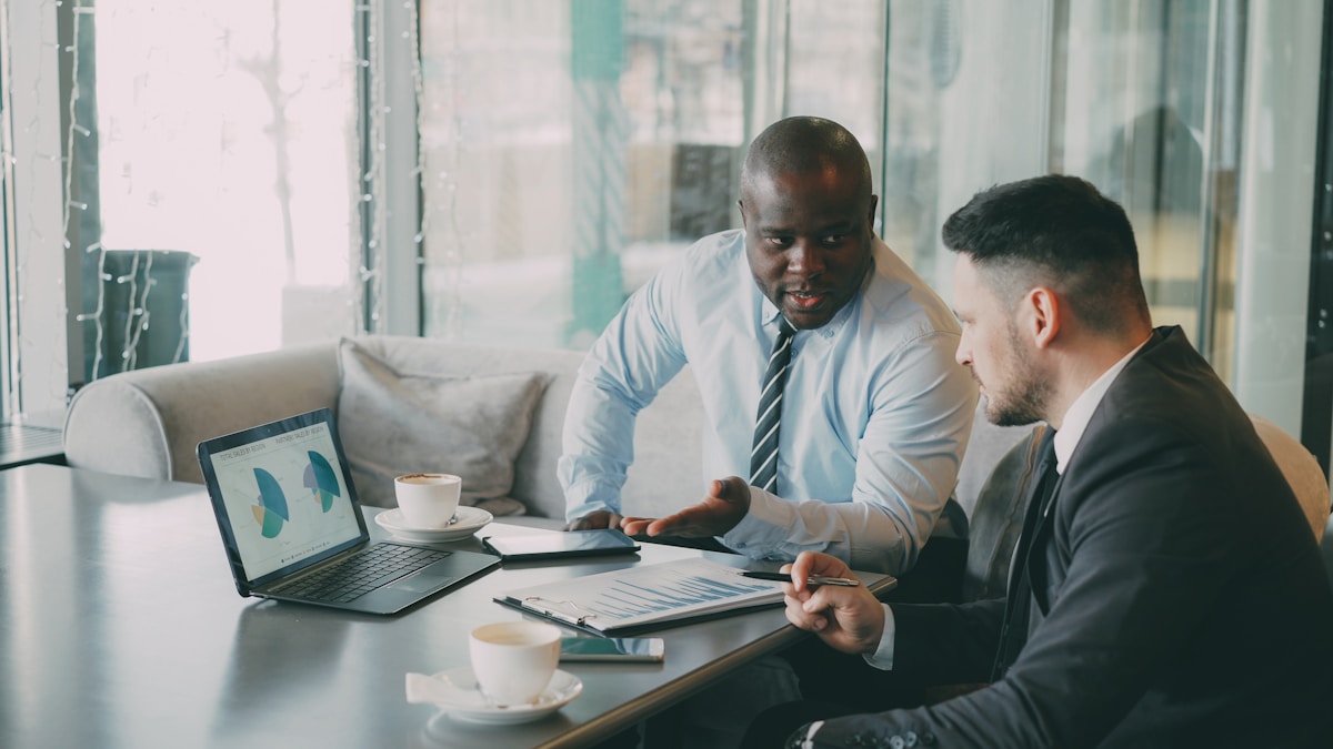 Two businessmen discussing charts on a laptop.