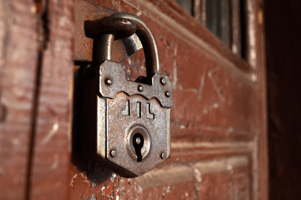 Cadenas rouillé en métal sur une porte en bois décrépie.