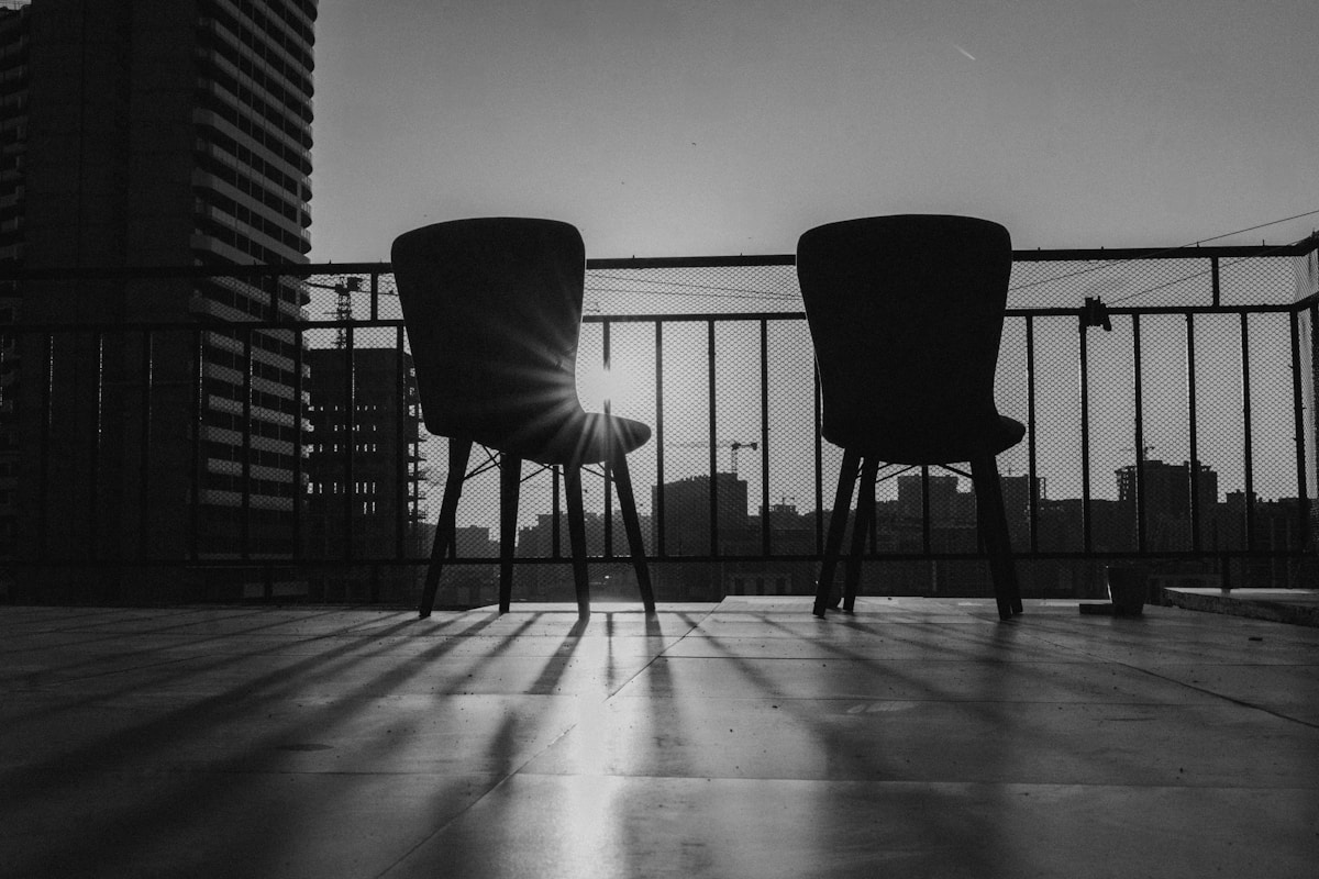 Chaises en ombre sur un balcon avec vue sur la ville.