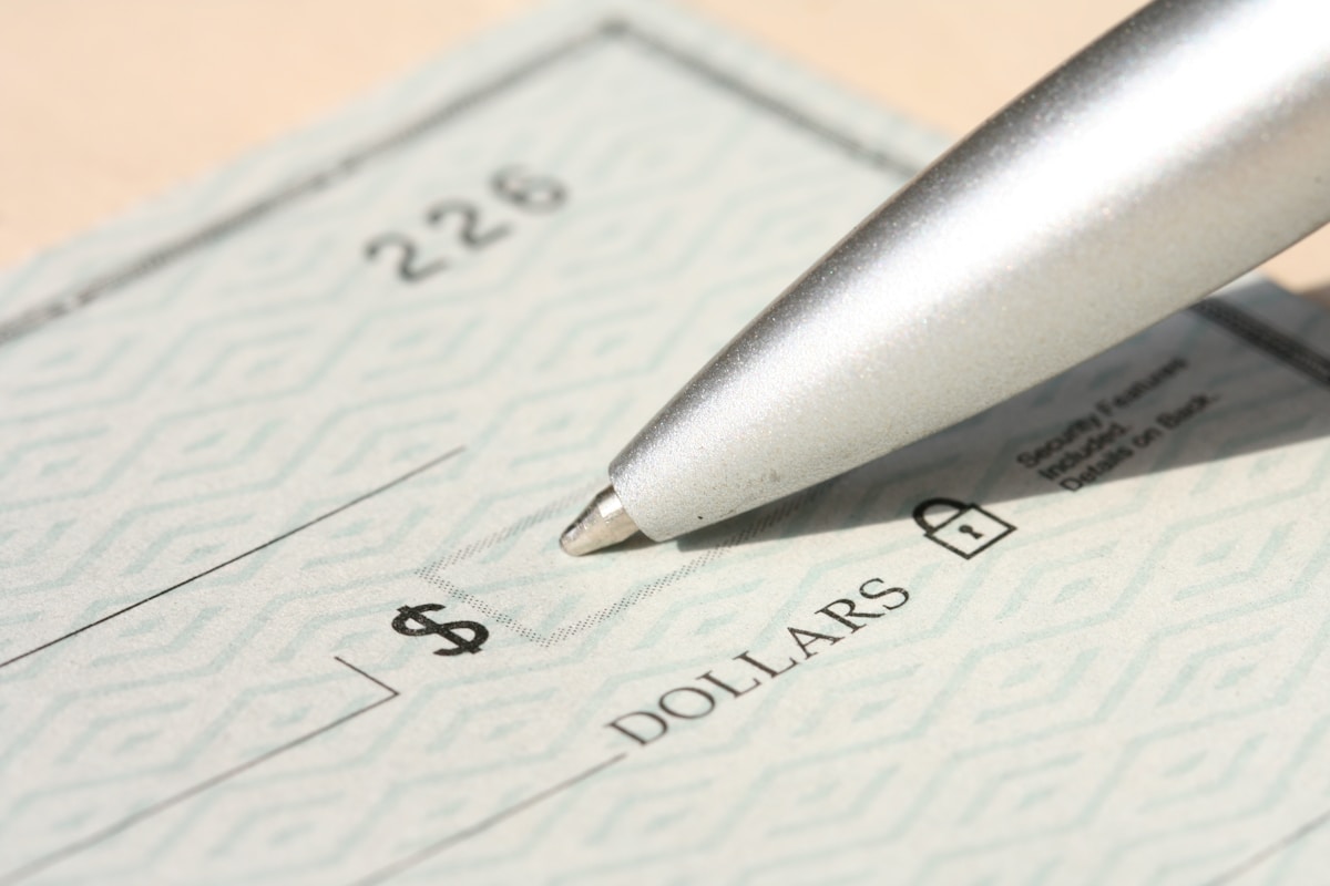 Formulaire de chèque avec un stylo argenté pointé sur le montant en dollars.