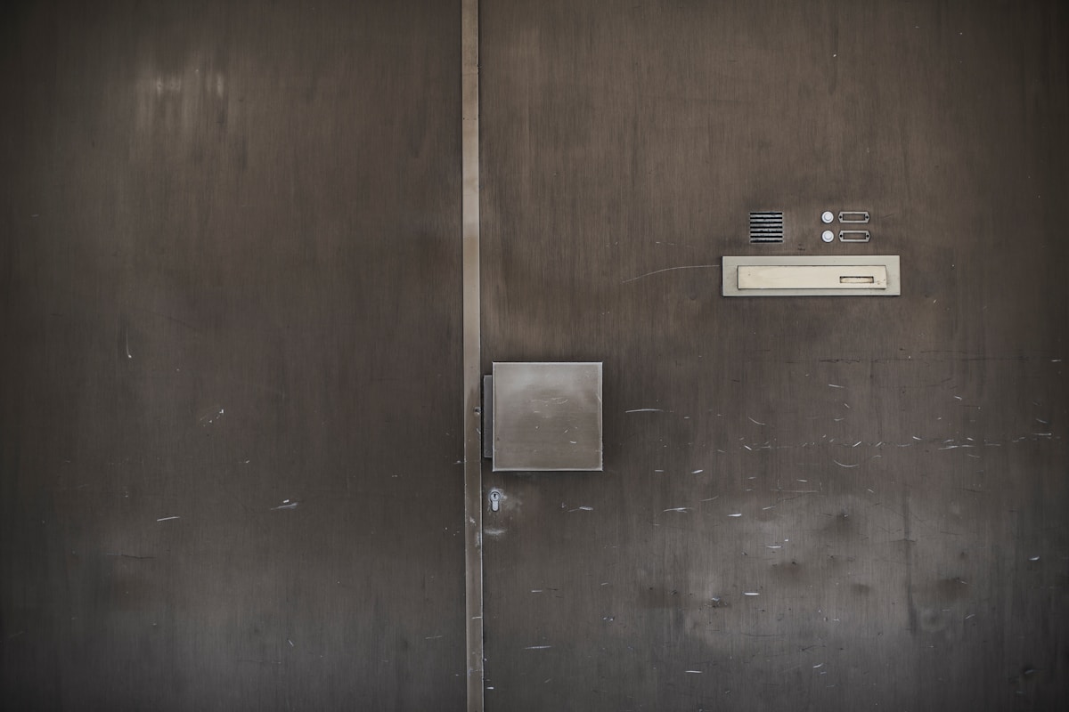 Porte métallique grise avec interphone et boîte aux lettres.
