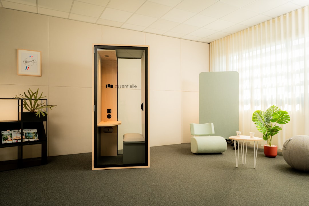 contrôle accès biométrique bureau moderne - Modern office with soundproof phone booth and seating.