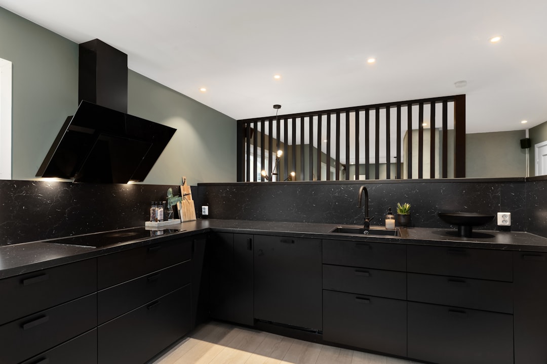 verrière atelier sur mesure - A kitchen with black cabinets and counter tops