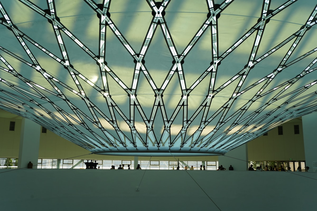 Plafond géométrique en verre et métal, espace intérieur lumineux.