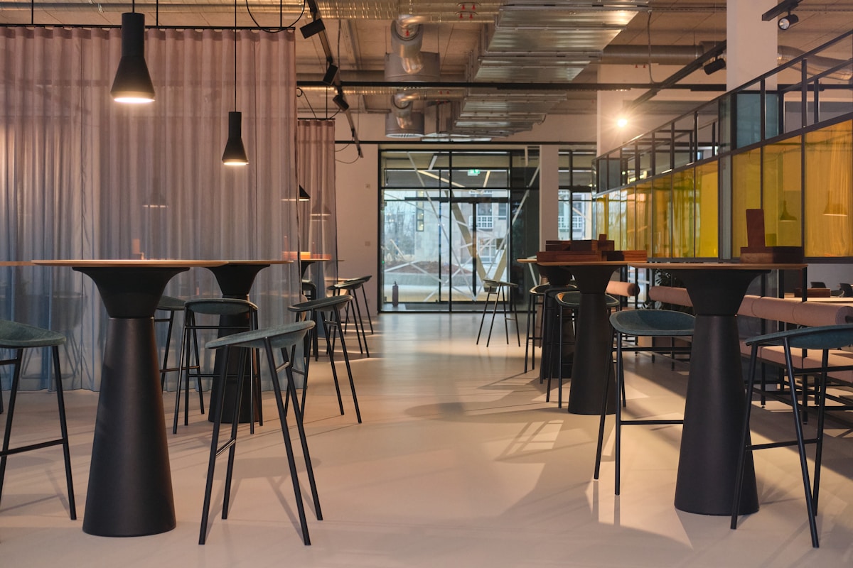 Espace de travail moderne avec tables hautes et chaises noires.