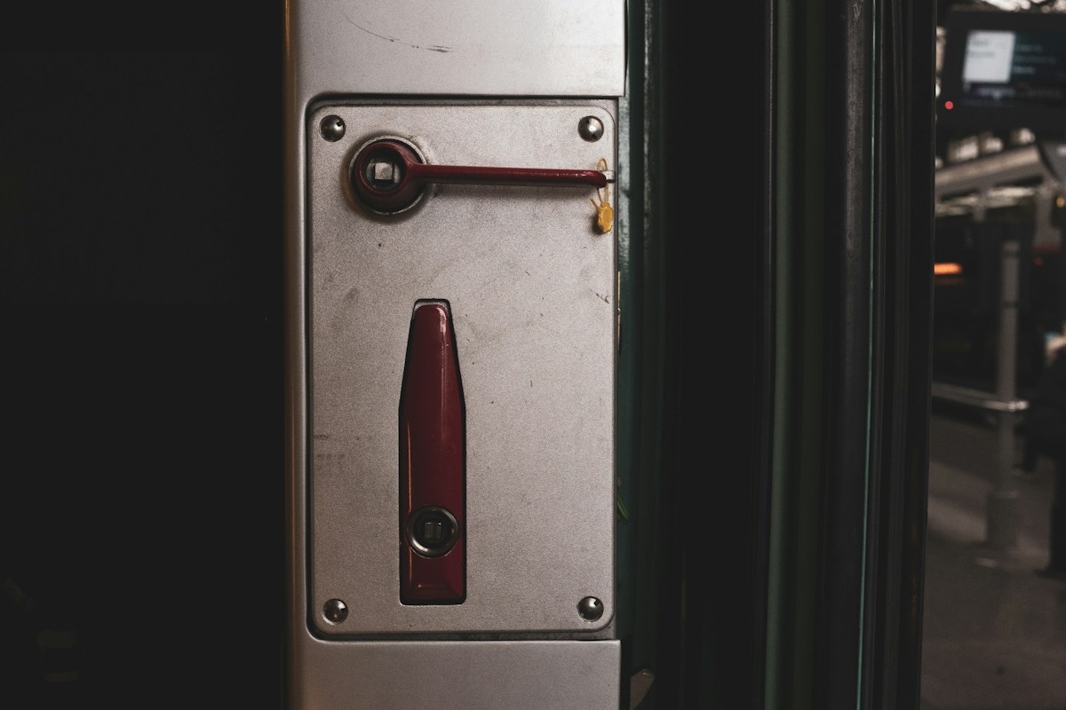 Poignée rouge sur panneau métallique près d’une porte de métro