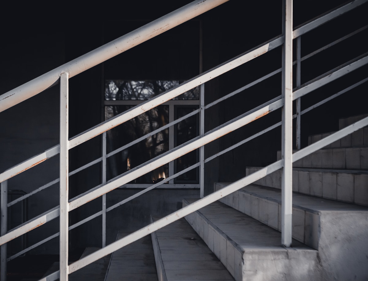 Passerelle métallique sombre avec fenêtres réfléchissantes dans un environnement sombre.