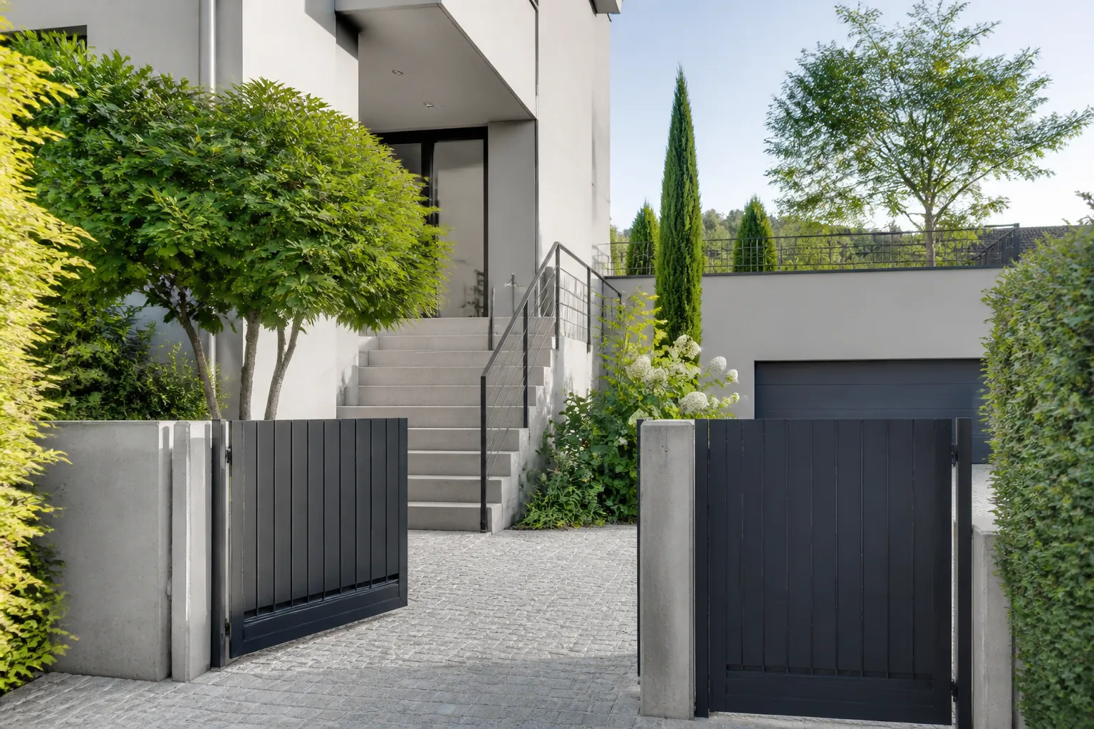 Entrée de maison moderne avec escalier, arbres et portail noir.