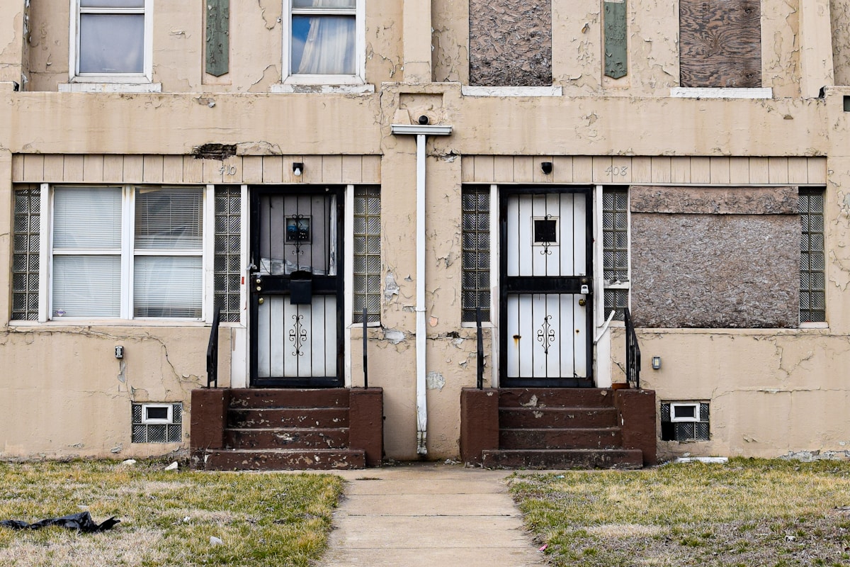 Façade délabrée d'un bâtiment avec portes et fenêtres endommagées.