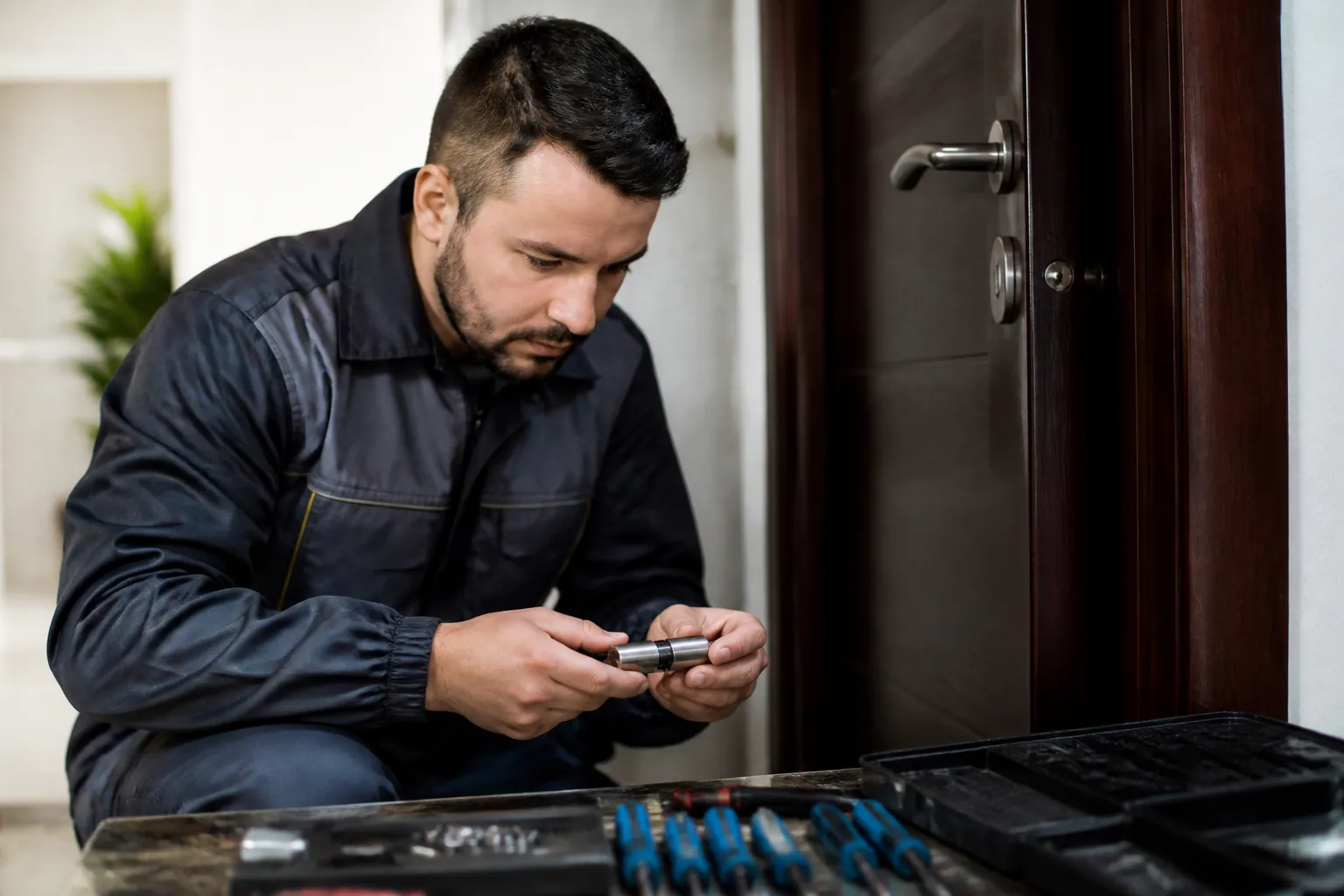 Homme en veste noire réparant un équipement électronique à la porte.