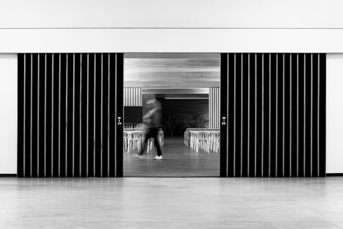 Salle de conférence minimaliste avec rideaux noirs et chaises blanches.
