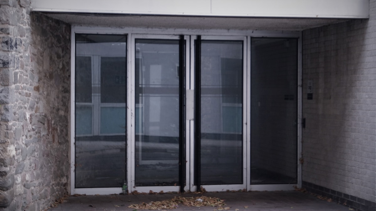 Porte en verre et en métal d'un bâtiment en pierre.