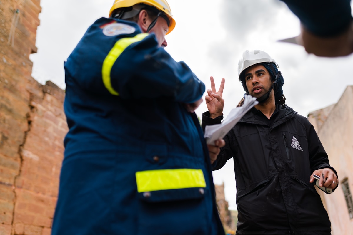 Deux travailleurs du bâtiment en discussion sur un chantier.
