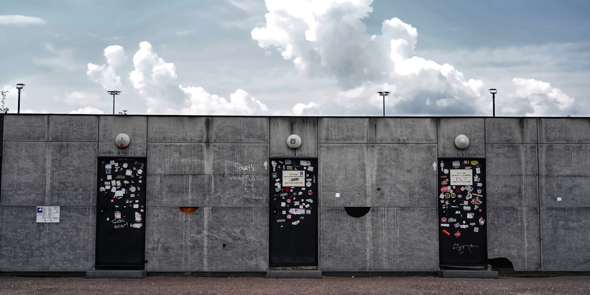 Murs de béton gris avec graffitis et affiches.