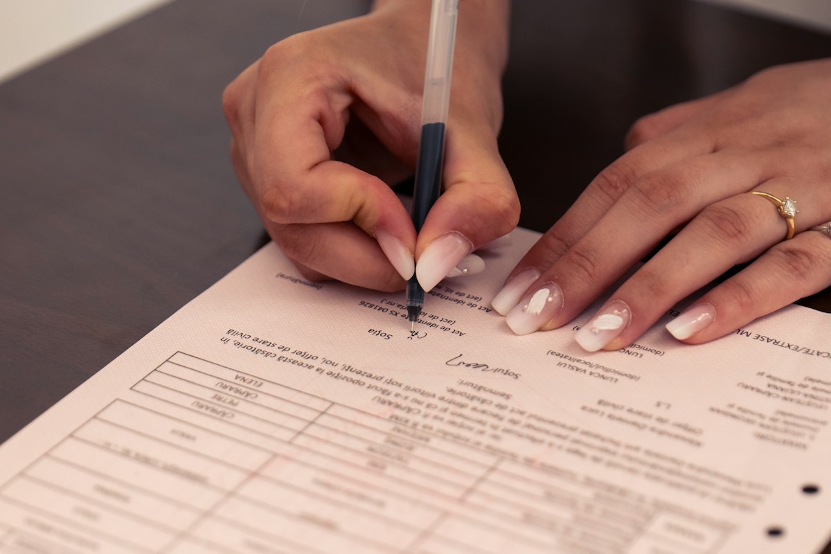 Femme signant un document officiel avec un stylo noir.