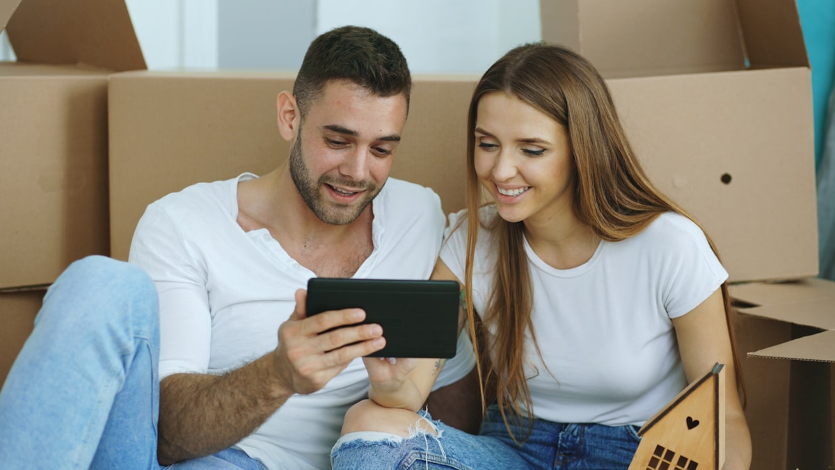 Couple heureux utilisant un téléphone portable dans un nouvel appartement.