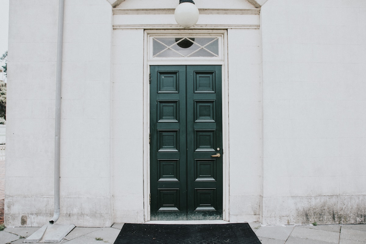 Porte d'entrée verte ornée de panneaux sculptés.