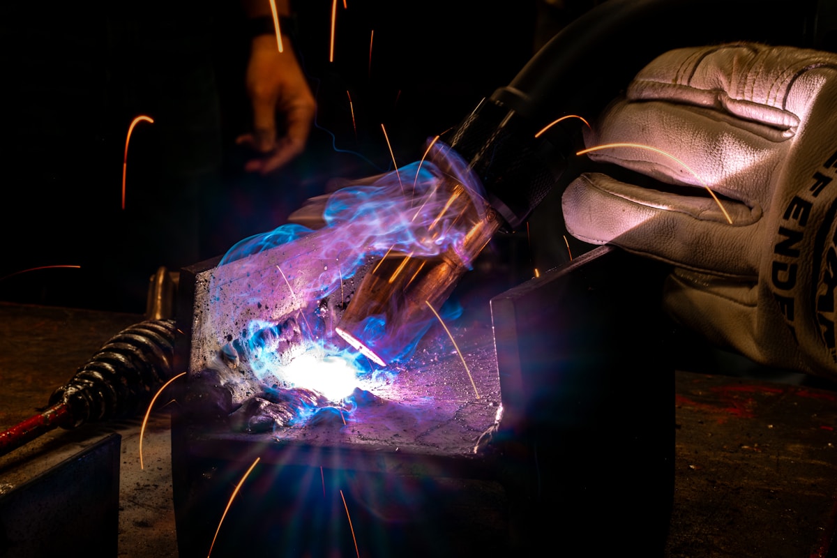 Soudage industriel avec étincelles et flammes colorées.